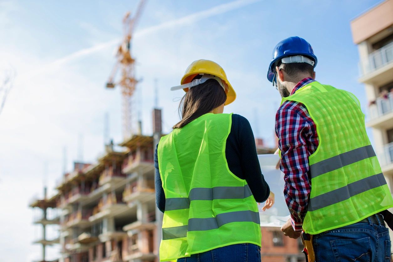 Two people in yellow vests and a blue helmet