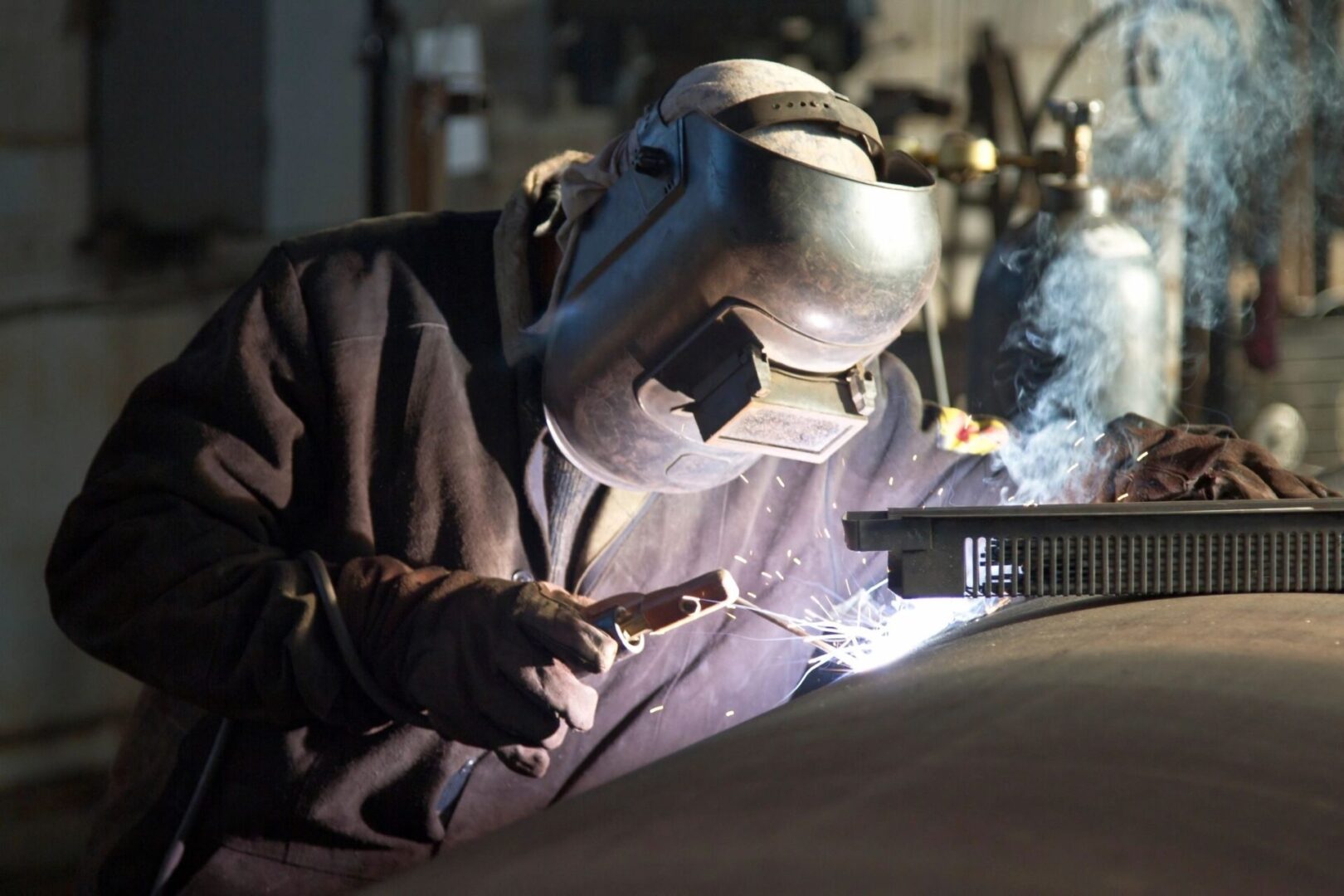 A man welding in the garage with a mask on.