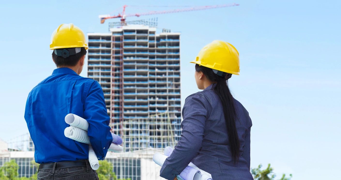 Two people in hard hats looking at a building